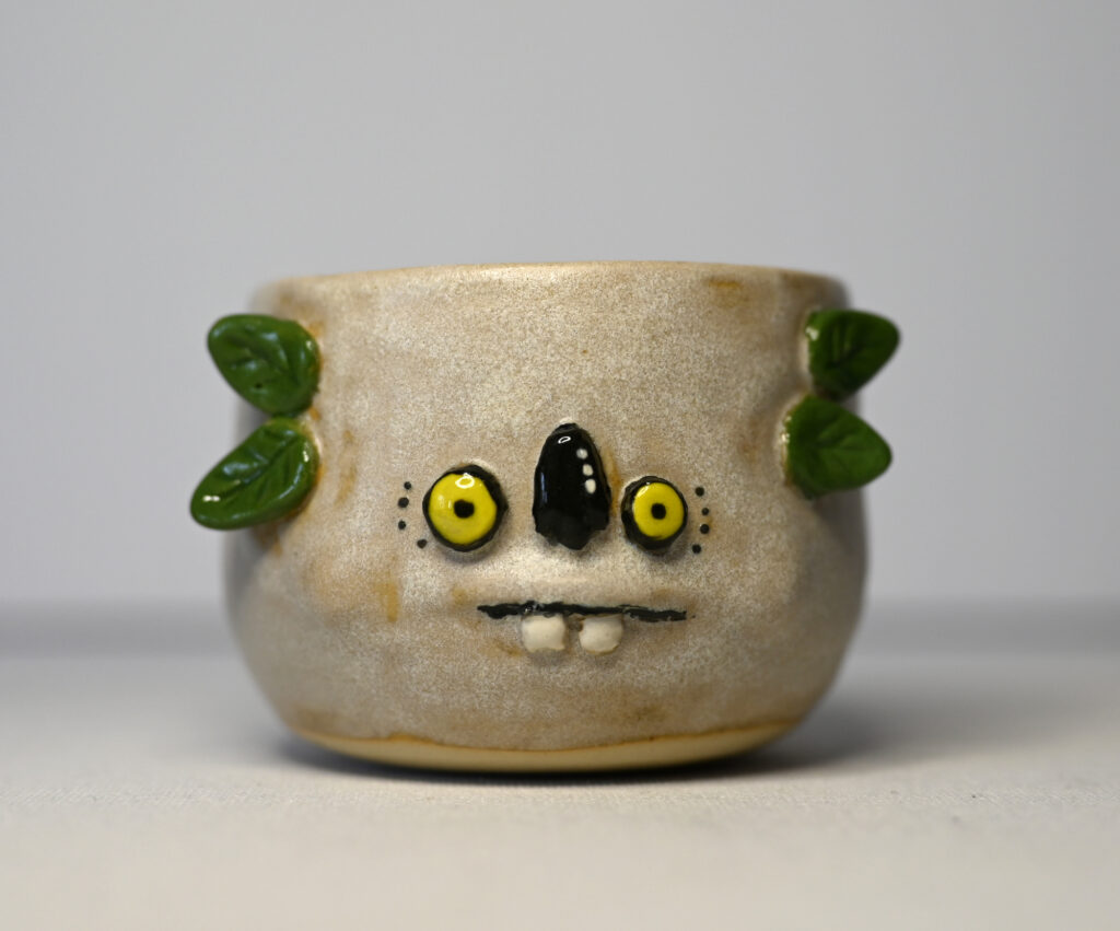 Albino Koala by Fatin Rahmouni, handmade ceramic Monstermug with pale glaze, yellow eyes, black nose, small teeth and green sculpted ears.